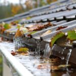 Rainwater overflowing from a clogged white gutter